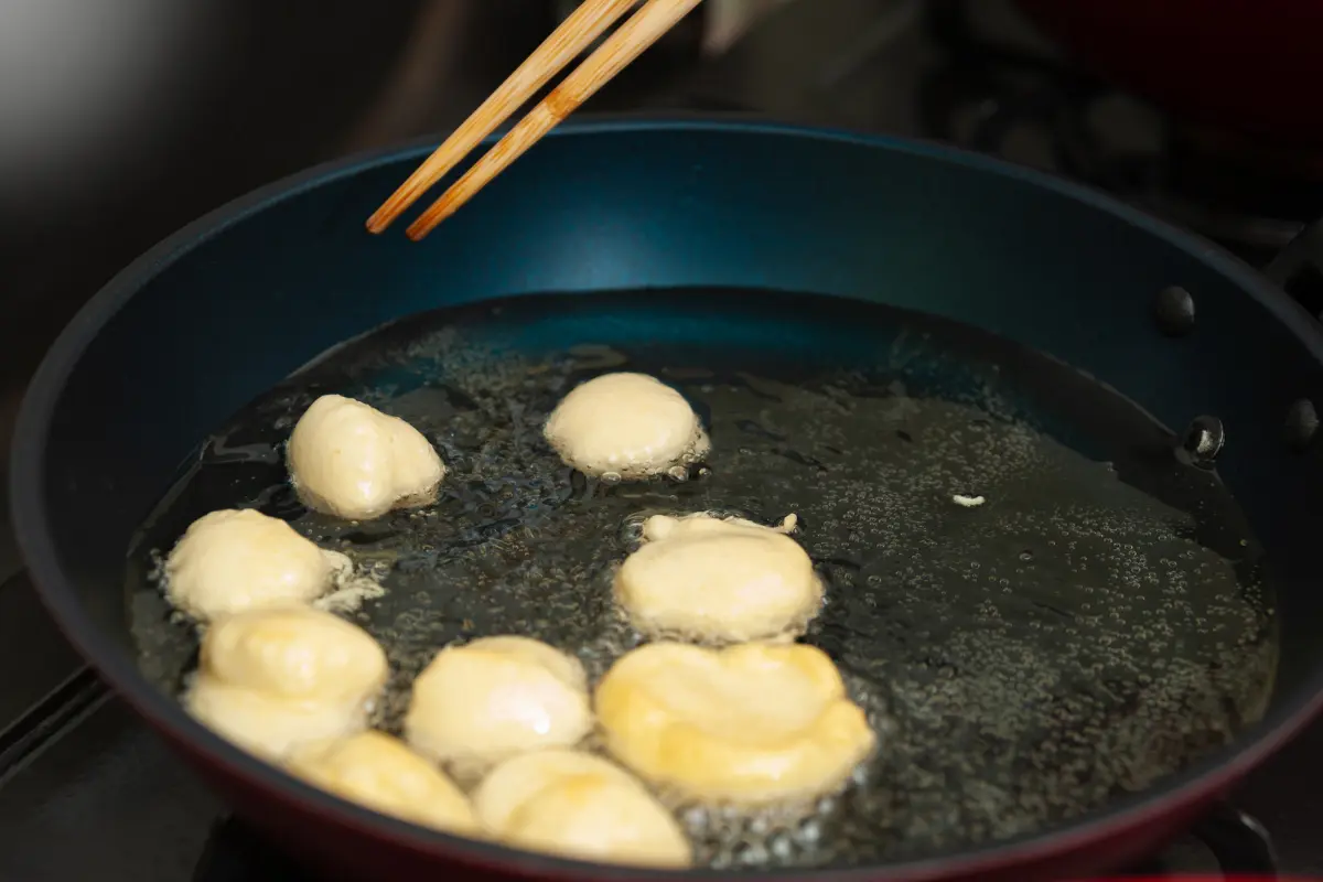 Bolinhos de chuva fritando no óleo quente.