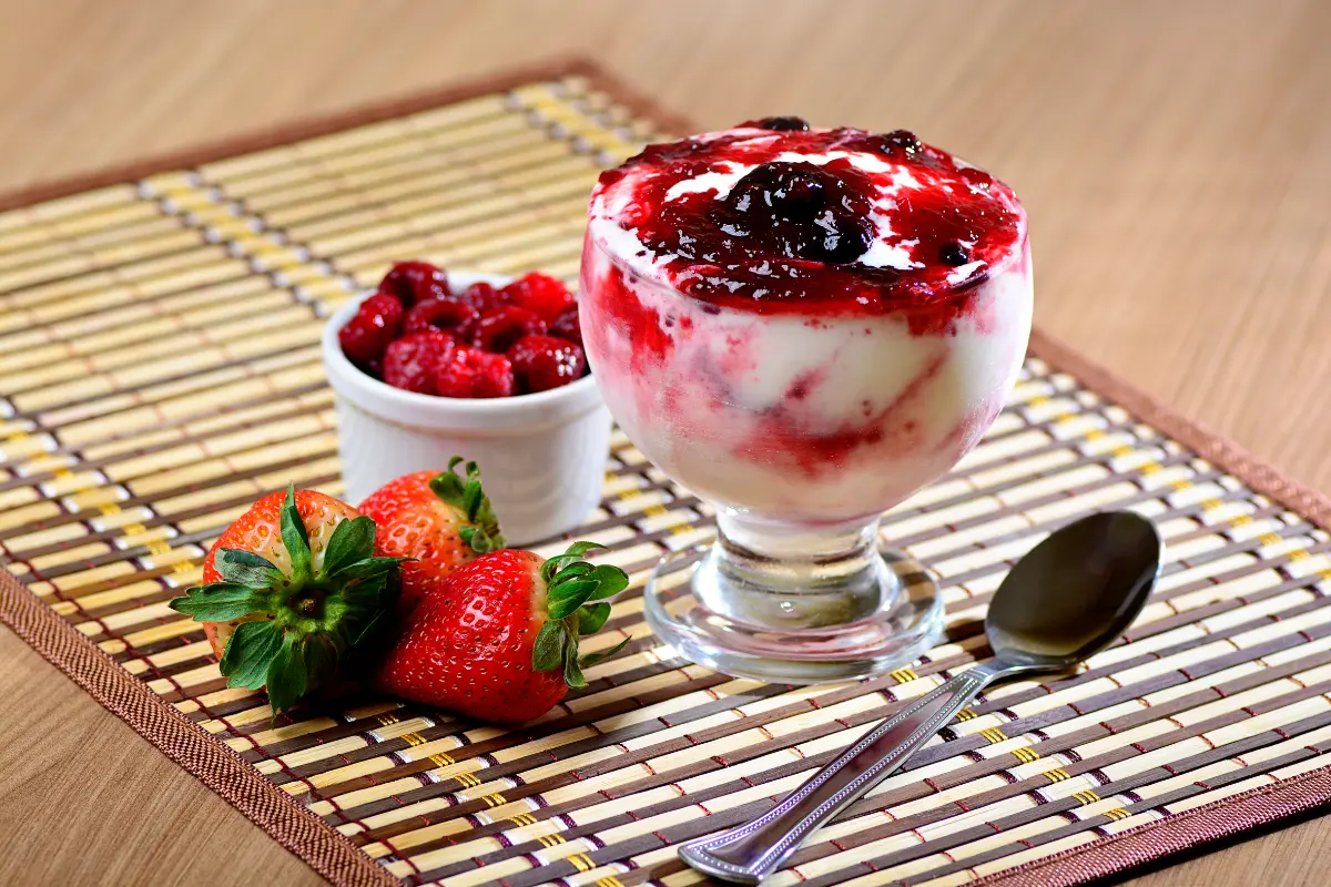 Sobremesa de gelatina com leite condensado e creme de leite decorada com frutas.
