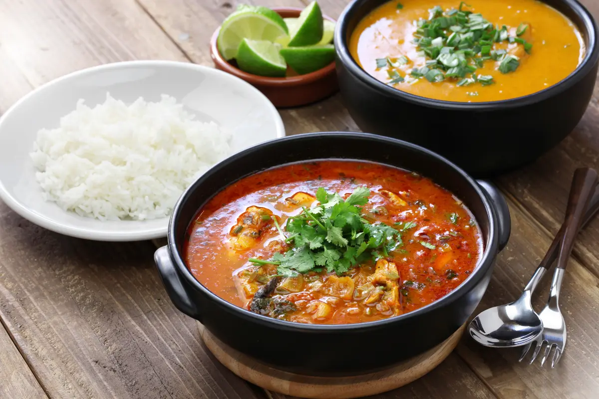 Moqueca baiana com cores vibrantes, servida com pirão e pimenta artesanal.